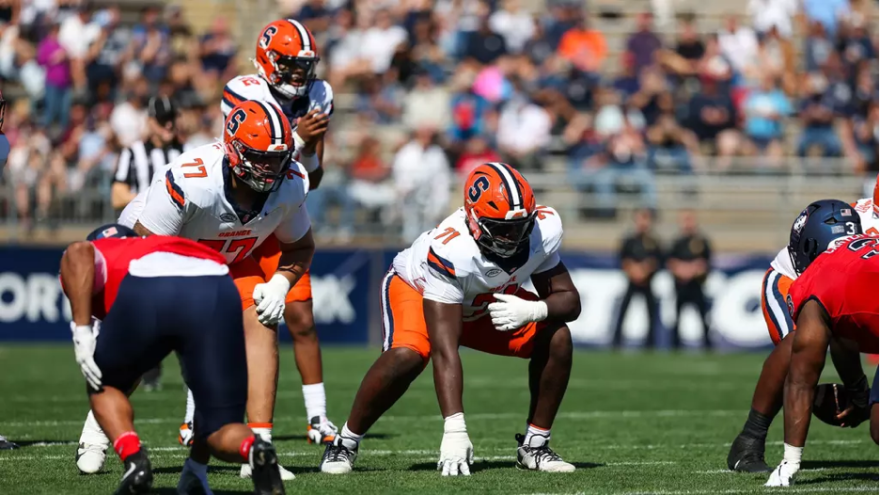Offensive linemen Jayden Mann (71, White), and Cam Pringle (77, White) before a snap.