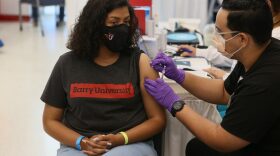 Ashley Dever, a sophomore at Barry University, receives a Pfizer-BioNtech COVID-19 vaccine from Jason Rodriguez, a pharmacy student iin Miami, Florida. 
