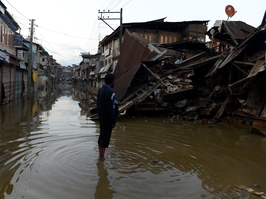 A Kashmiri resident stands in flood waters on Sunday as he looks at a house that collapsed following the heavy rainfall that hit the area last week.
