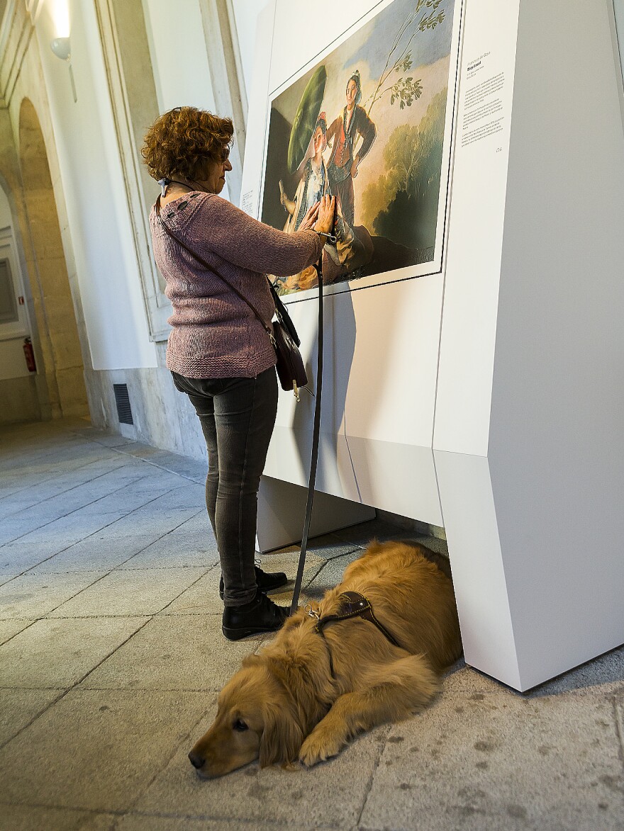 A blind visitor touches a copy of Francisco Goya's 1777 masterpiece, <em>The Parasol</em>.