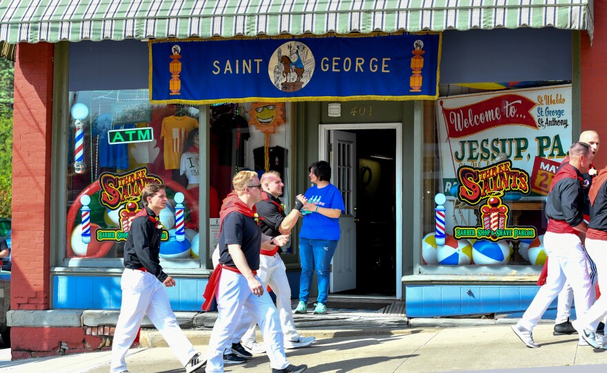 Racers walk past Three Saints Barber Shop.