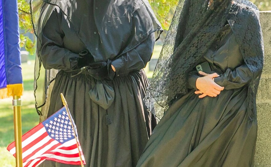 Lisa Smith, left, of Traverse City, and Angel Sibel of Leroy, stand near the Oakwood Cemetery grave of Corporal Lyman Snow dressed as mourners from the 1860s during a ceremony dedicating Snow's new gravestone on Monday morning in Traverse City.