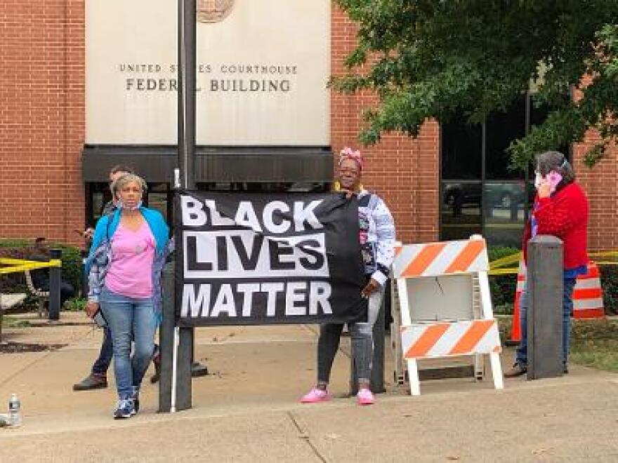 Demonstrators stand outside the federal court building in Charlottesville as 24 alleged organizers of Unite the Right go on trial inside.