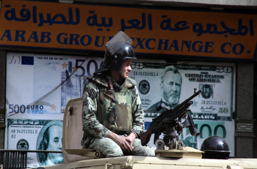 An Egyptian soldier on an armored vehicle guards an exchange office in Cairo on Monday. Tensions between the U.S. and Egypt are rising over Cairo's investigation of aid workers, many of them American. An Egyptian Cabinet minister, Faiza Aboul Naga, recently accused the U.S. of directly funding pro-democracy groups in order to create chaos in Egypt.