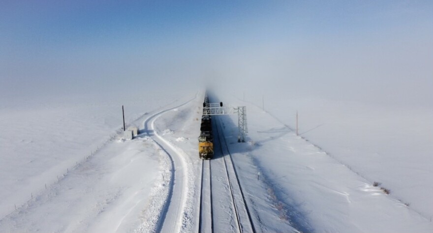 A train on train tracks on a snowy landscape. 