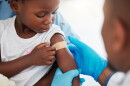 Doctor, healthcare expert and medical worker with plaster on arm of sick child after covid vaccine, help with medical emergency and consulting with patient at hospital. Girl with bandage after injury.