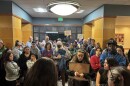 A crowd of protestors with signs gathers inside a hallway.