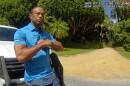 Tiger Woods in a blue polo shirt performs a field sobriety test while leaning on a white SUV 