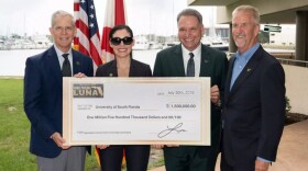 Four people standing behind a large check, smiling.