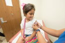 A health care worker places a bandage on a child after giving a vaccination shot. New federal guidance to reduce the number of recommended childhood vaccines from 17 to 11 comes as states including Florida are already charting their own course on vaccine policy.