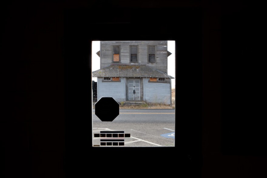 A shuttered granary seen through the door of a rural Oregon post office, which is also slated for closure.
