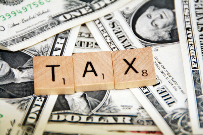 Tiles spelling "TAX" lay on a background of money.