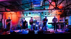 Seven musicians perform on stage at a small music venue.