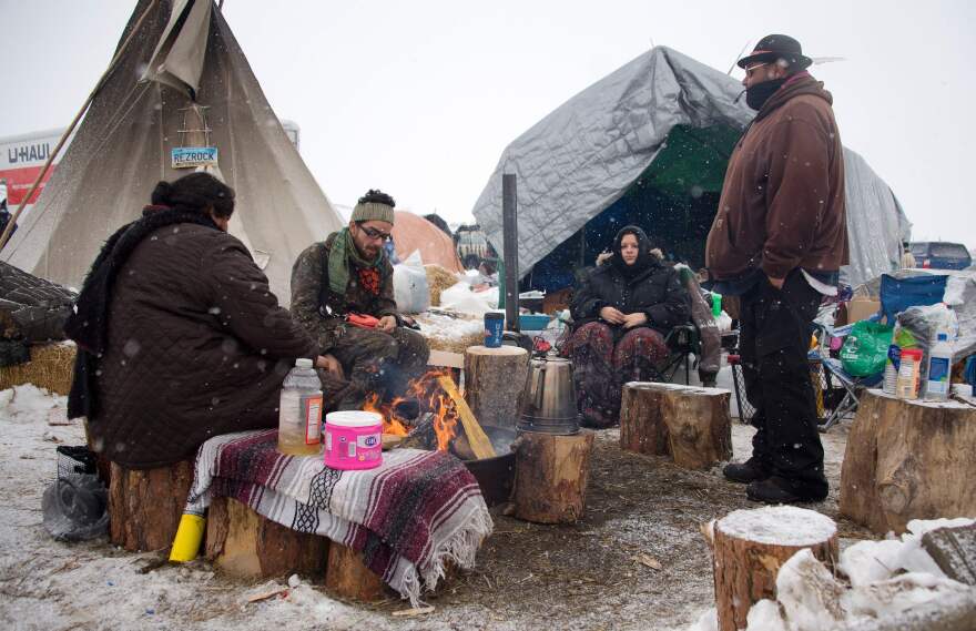 Protesters sit around a campfire as it snows at Oceti Sakowin camp on Monday.