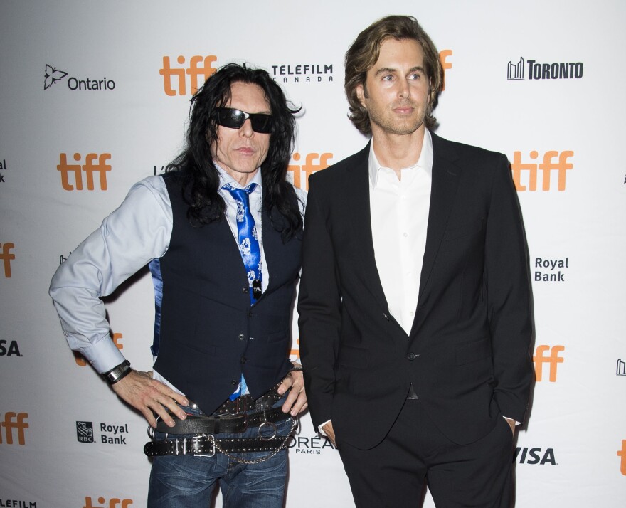 Two men pose for a photo on the red carpet of a movie premiere