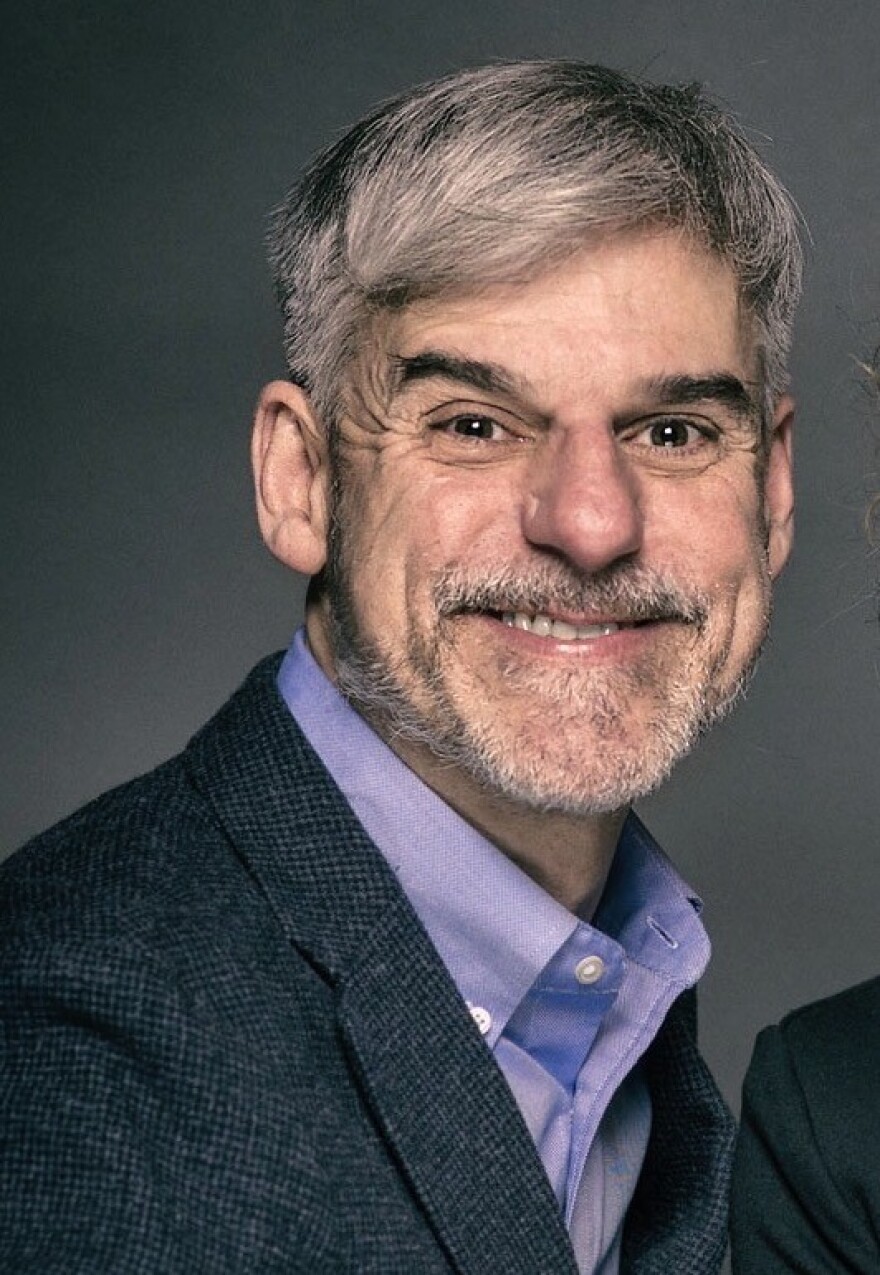 Marc Garber is wearing a collared shirt and suit jack, smiling for a headshot photo.