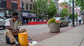 A street performer plays for donations as restaurants and bars begin to reopen in the wake of the COVID-19 pandemic, Saturday, May 16, 2020, in Cincinnati.