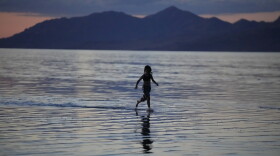 FILE - A young person runs through the Great Salt Lake on June 15, 2023, near Magna, Utah. A coalition of environmental organizations sued the state of Utah on Wednesday, Sept. 6, 2023, based on accusations that it is not doing enough make sure enough water gets to the shrinking Great Salt Lake. (AP Photo/Rick Bowmer, File)