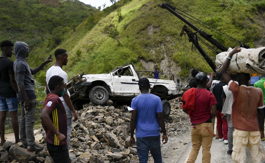 A crane removes a truck from a pile of rocks after landslides triggered by a 7.2-magnitude earthquake that hit four days prior in River Glass, Haiti, Wednesday, Aug. 18, 2021.