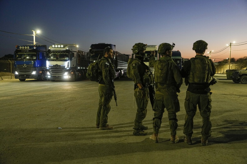 Israeli soldiers stand near trucks carrying humanitarian aid just before they cross into the Gaza Strip at Erez crossing in southern Israel, Monday, Oct. 21, 2024.