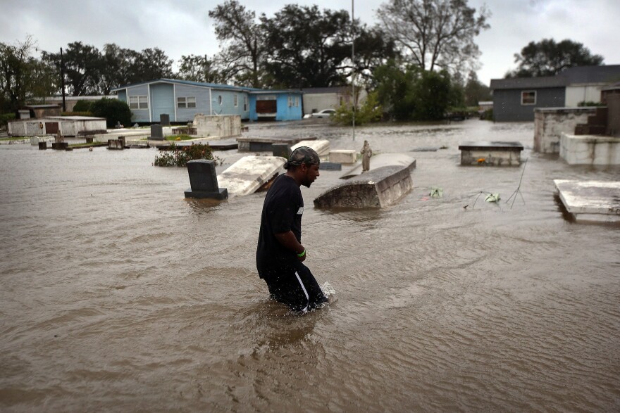 Errol Ragas walks past a cemetery to recover dry blankets from his home as rising waters from Hurricane Isaac flood the neighborhood of Oakville in Plaquemines Parish, Louisiana.