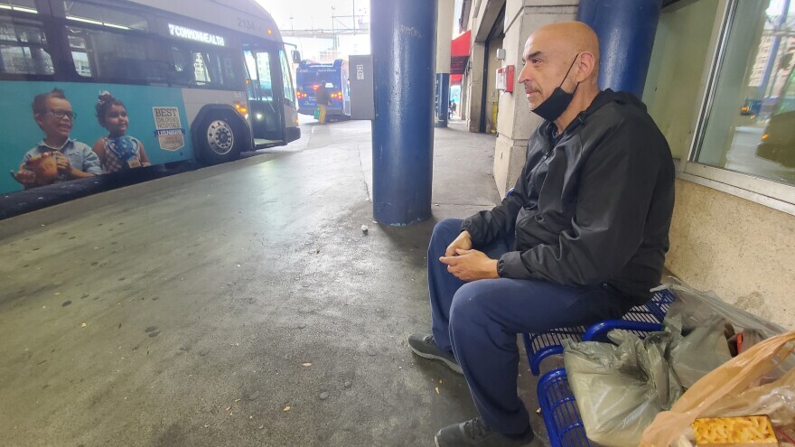 Jose Leon waits for a bus uptown. He's trying to save $1,000 for a used car.