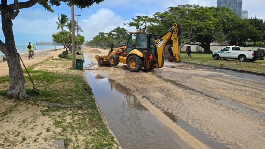 Crews clear sand and debris from Ala Moana Regional Park on Tuesday morning.