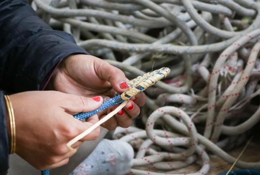 A craftswoman interweaves discarded climbing rope with Moonj, a traditionally harvested wild grass, to make a decorative item.