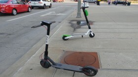 A Bird and a Lime scooter sit on a Downtown sidewalk, July 2019.