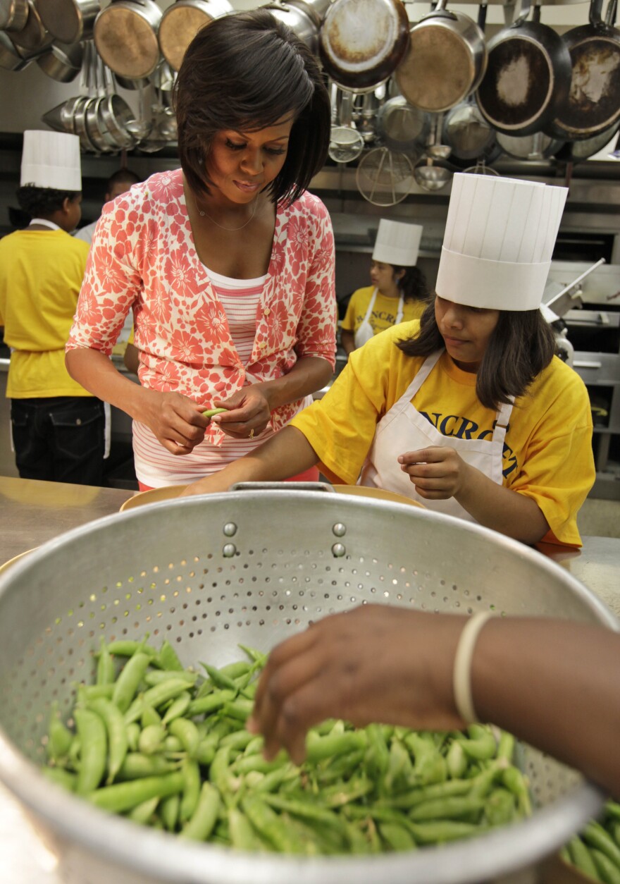 Obama shells peas with fifth graders from Bancroft Elementary School after they harvested vegetables from the first lady's garden on the South Lawn of the White House.