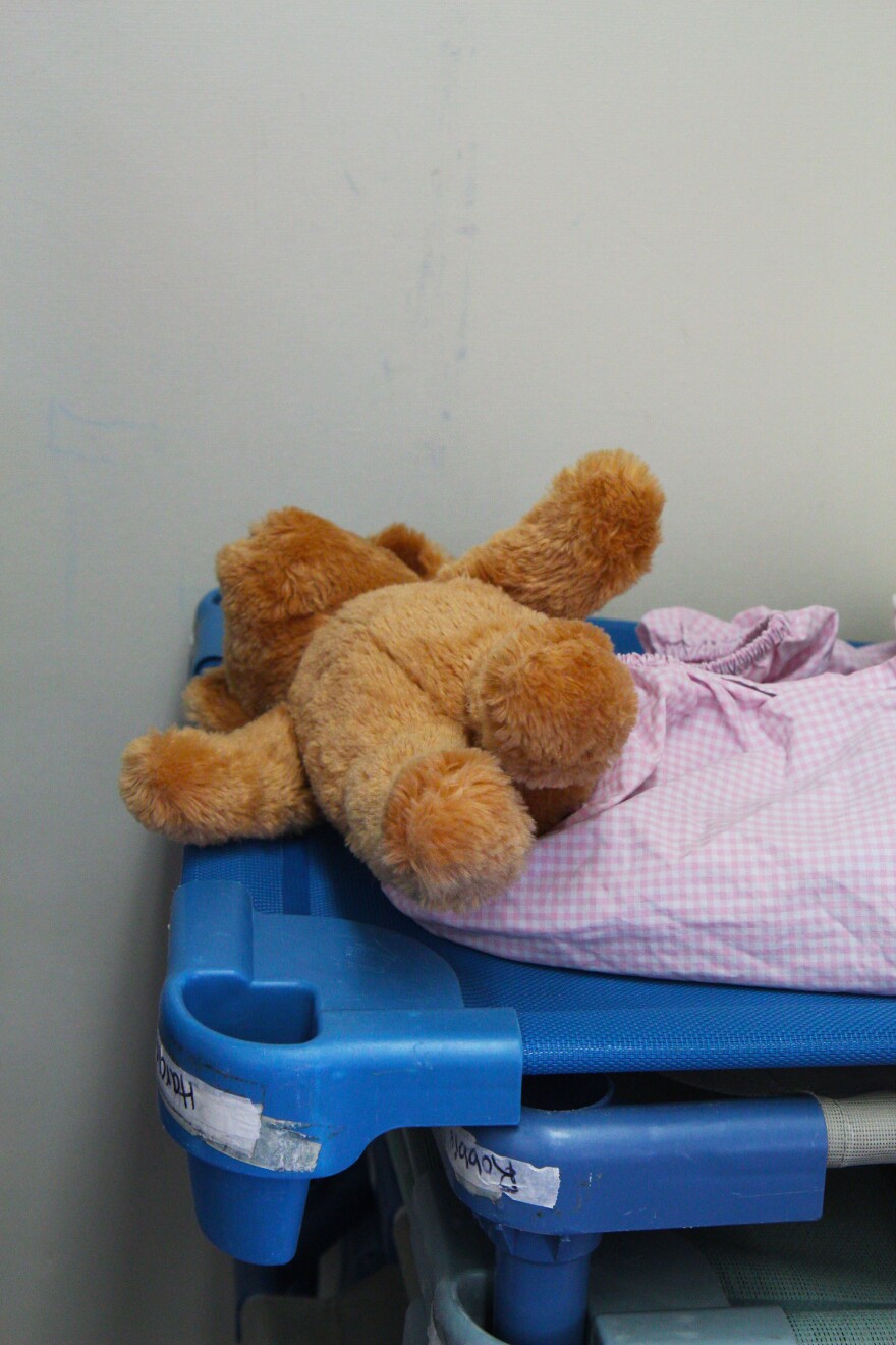 A teddy bear on a cot.