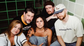 The five members of Des Moines band Lady Revel sit on the floor and look at the camera