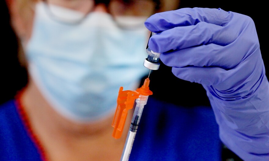 A medical professional wearing a mask prepares a COVID-19 vaccine