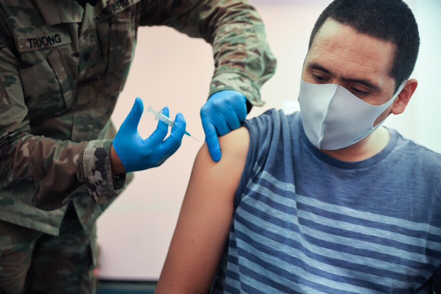 Maryland National Guard Specialist James Truong (L) administers a Moderna coronavirus vaccine on May 21, 2021 in Wheaton, Maryland. People vaccinated with Moderna likely need a booster to keep up their protection against the new omicron variant.