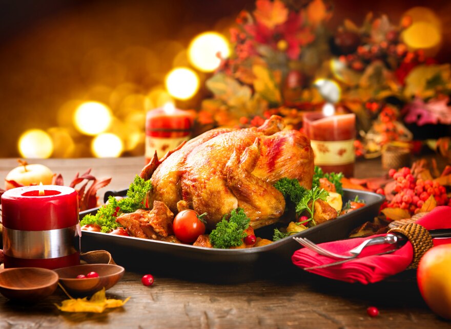 A cooked turkey on a dining table surrounded by Christmas decorations.