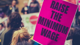 This stock photo shows a sign calling for an increase in the minimum wage at a rally.