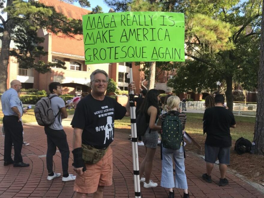 UF alum Jonathan Coron, 60, of Gainesville, stands with his poster in protest outside of the University Auditorium. MOLLY CHEPENIK/WUFT