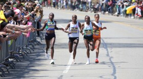 Boston Marathon winner Sharon Lokedi high-fives spectators in front of Boston College in Newton, Mass. while in the lead group of runners Monday, April 21, 2025. (AP Photo/ Jennifer McDermott)