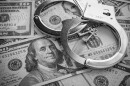 Pair of metal police handcuffs on US dollar banknotes 