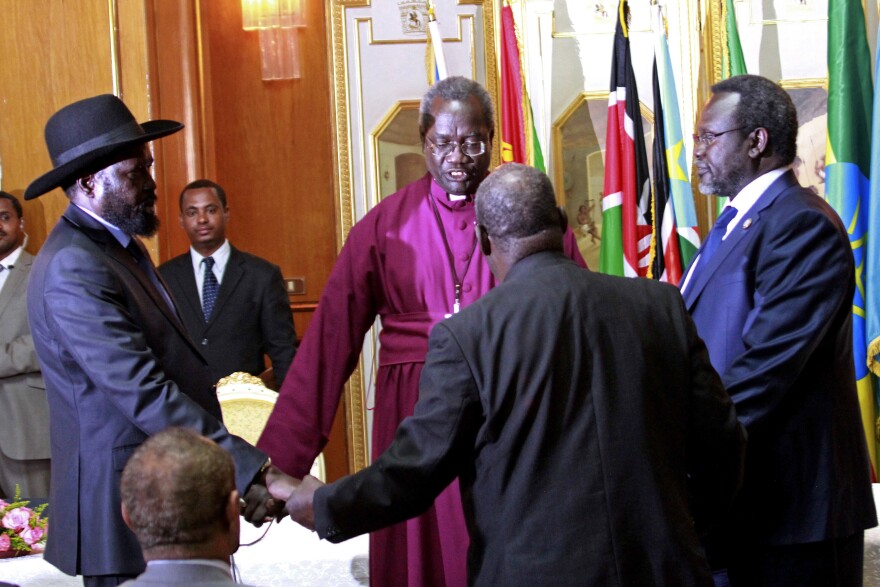 South Sudan's President Salva Kiir (left) and rebel leader Riek Machar (right) shake hands and pray before signing an agreement of the cease-fire of the South Sudan conflict on Friday in Addis Ababa, Ethiopia.