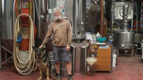 Ben Millstein and his dog, Phineas in the back room of the brewery, surrounded by beer stills, May 5, 2023. (Brian Venua/KMXT)
