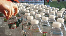 A hand reaches for one in a collection of plastic water bottles.