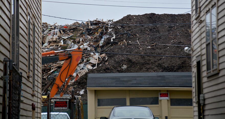 A pile of debris rises behind homes in East Cleveland. [Nick Castele / ideastream]