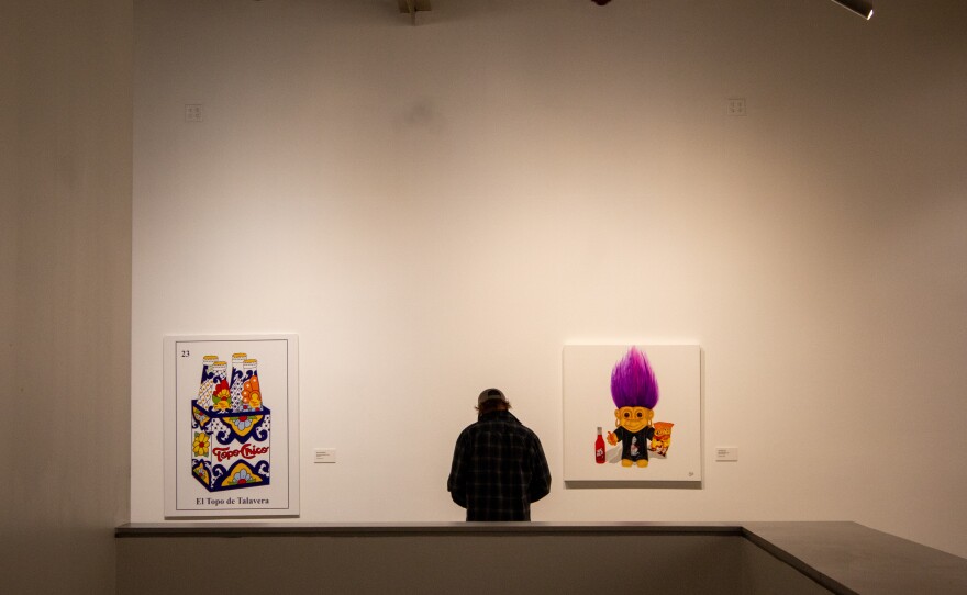 Guest on the second floor of the exhibition in front of a "El Topo de Talavera" by Symone Harvey and "Hot Cheeto Girl" by Uri Whitehead.