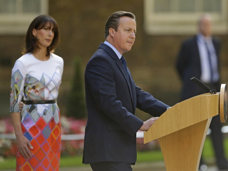 Britain's Prime Minister David Cameron speaks outside 10 Downing St., London, as his wife, Samantha, looks on. Cameron says he will resign by the time of the Conservative Party conference in the fall.