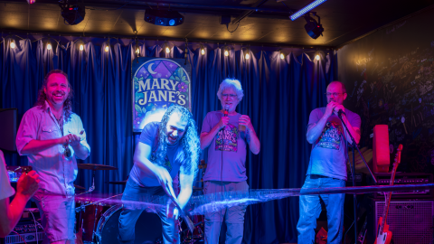 A group of men cutting a ribbon at a bar