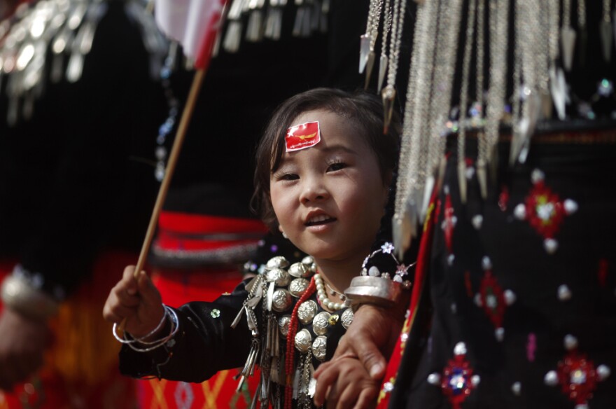 A girl from the Kachin ethnic group waves the flag of Suu Kyi's National League for Democracy as the democracy leader arrives in Namti village last week.