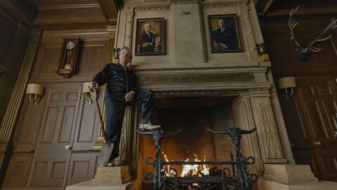 Tom Cruise poses with a shovel in front of a large fireplace.