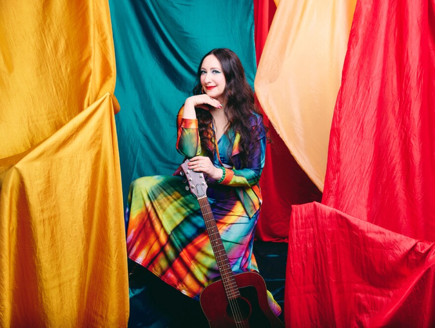 Singer Rachael Sage in a rainbow dress surrounded by colorful sheets and tapestries to reflect her latest album 'Canopy'. 