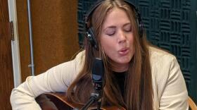 Shannon LaBrie playing her guitar with headphones on